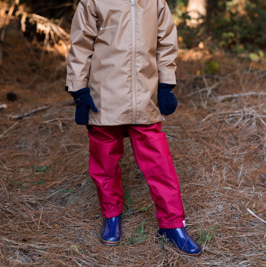 Girl standing in a forrest wearing waterproof outerwear.