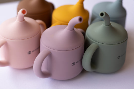 Set of colourful children's silicone cups with lids on a white background